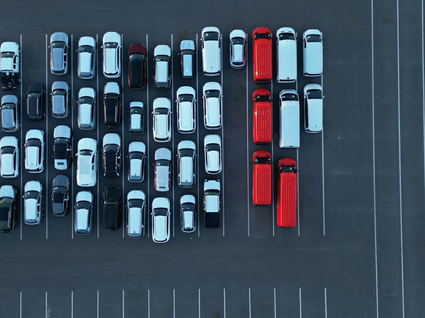 Aerial view of a parking lot with cars parked in rows, many of them generating transport emissions