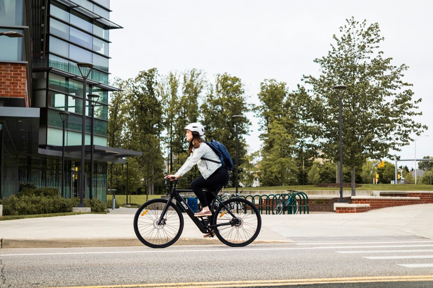 A person cycling with a helmet through an urban area next to bike racks