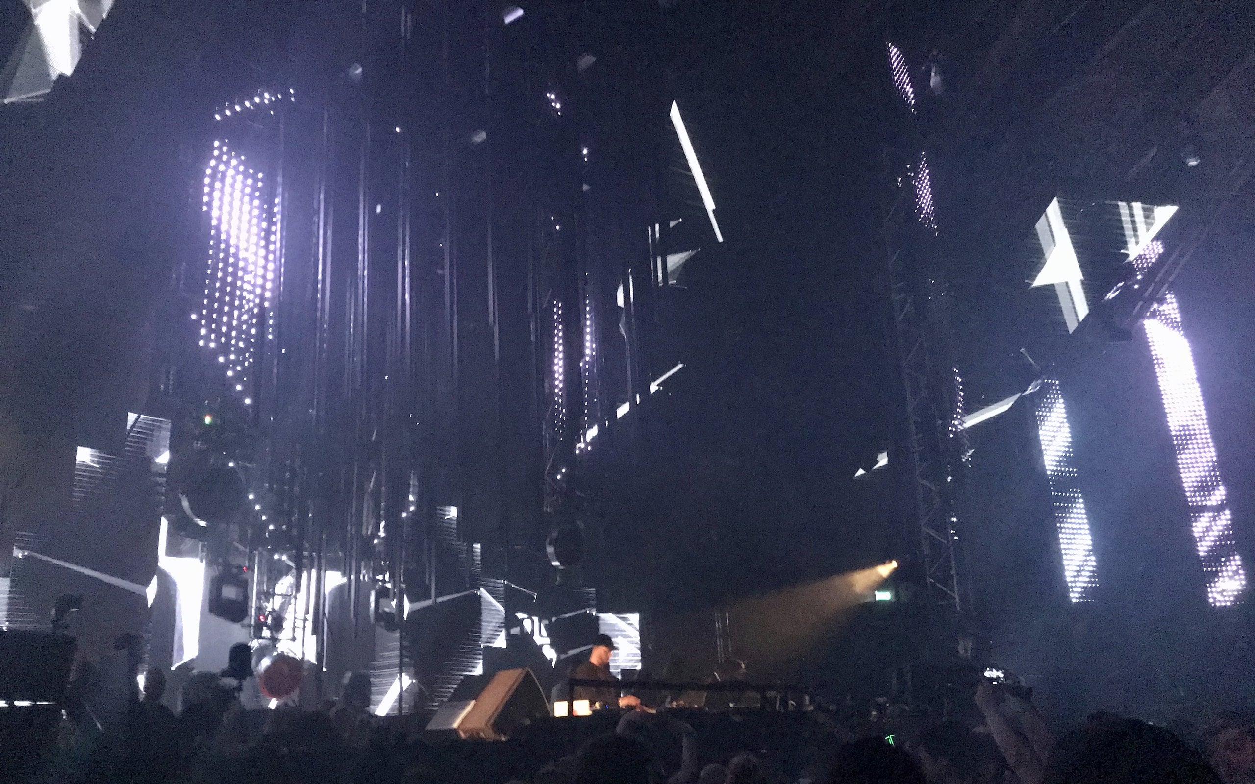 Electronic music stage with white and blue lights and the crowd (illustrative image)